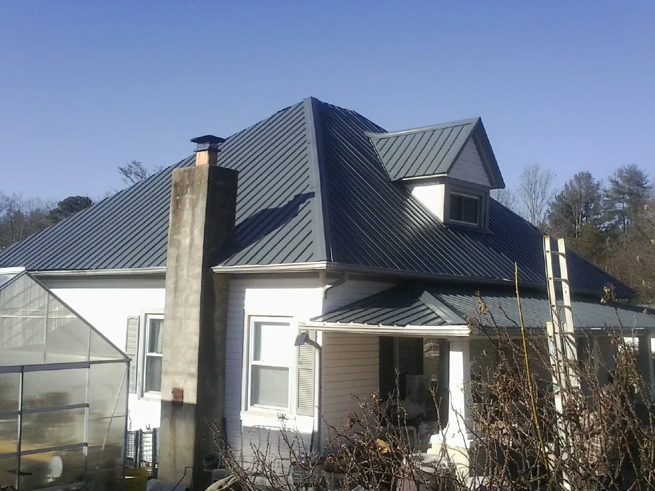 Dark blue standing seam metal roof on a white farmhouse with dormer — Slate & Tile Roof Repair by Roofing Brothers in Maryville