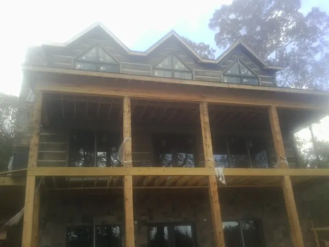 Dormers and porch framing on a large log home under construction — Roof Coating work by our crew in Maryville