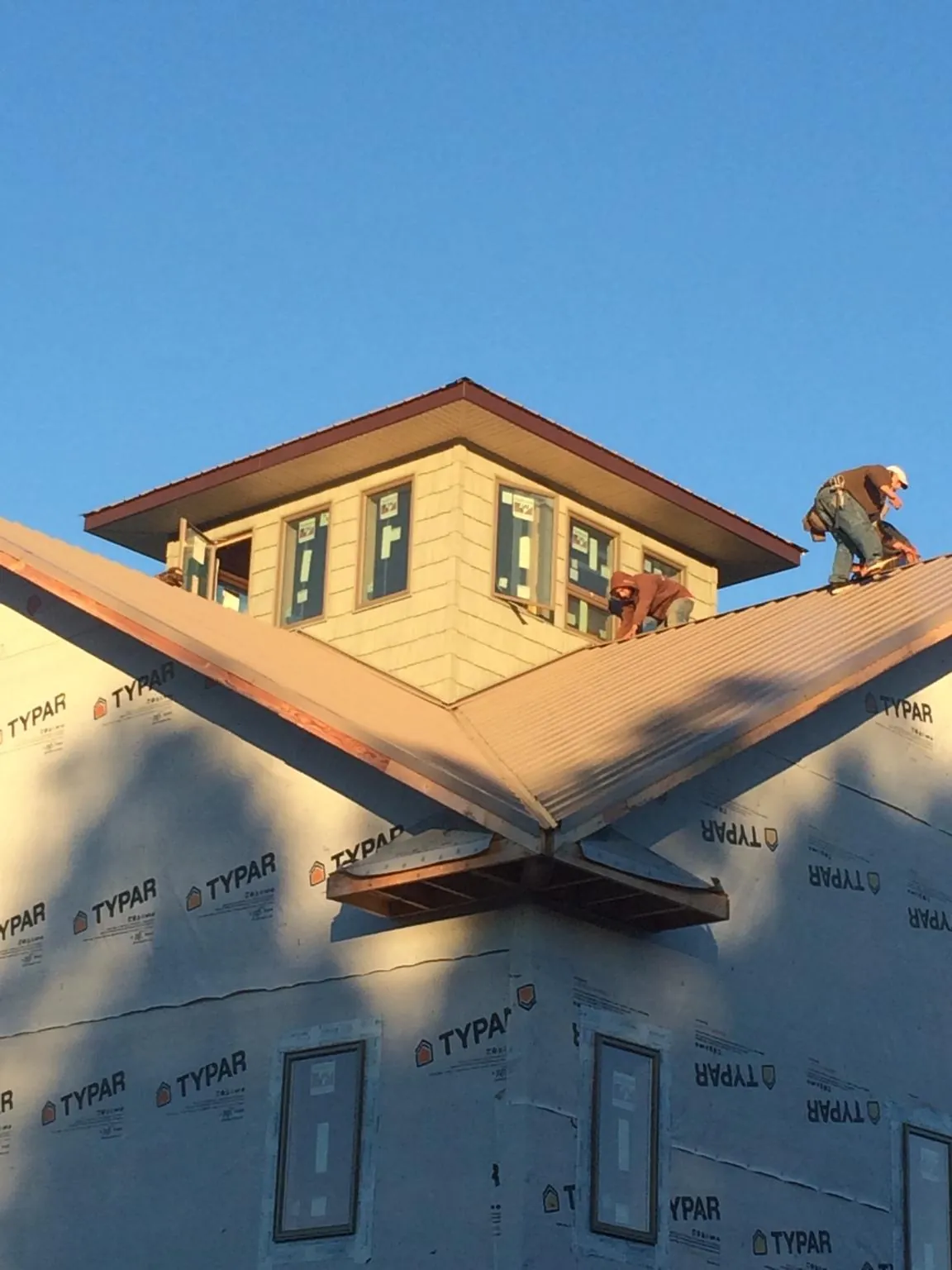 Roofers working around a rooftop cupola on a new metal roof at sunset — Roof Waterproofing in Maryville by Roofing Brothers